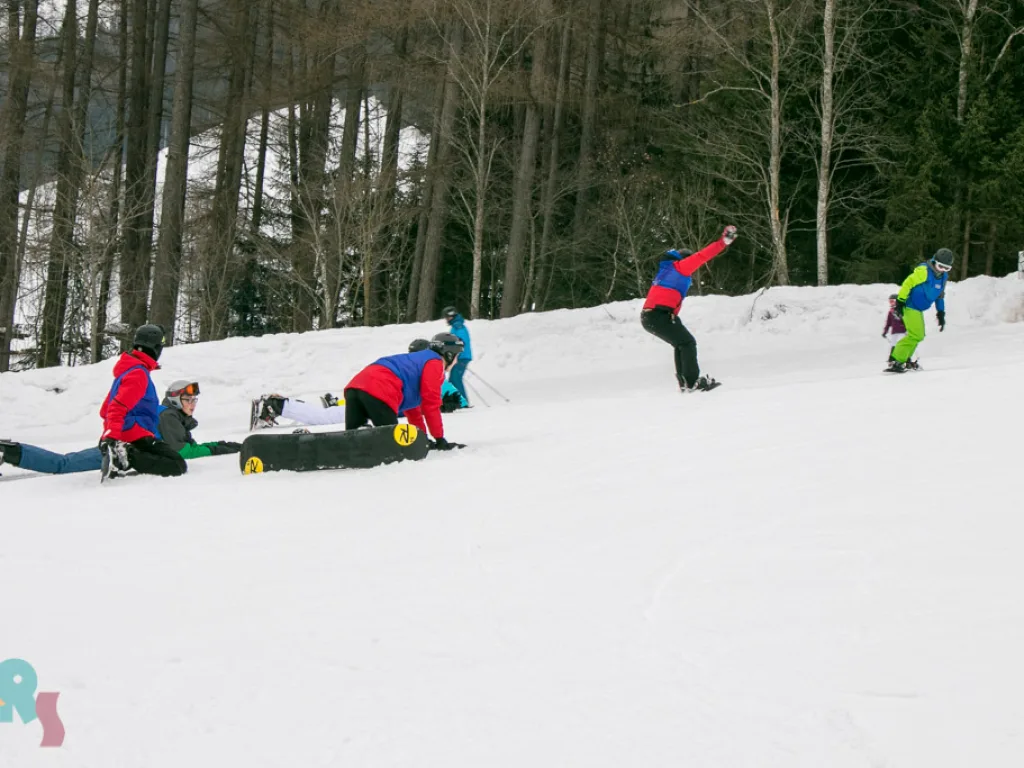 Jugendliche üben mit Snowboards am Hang.